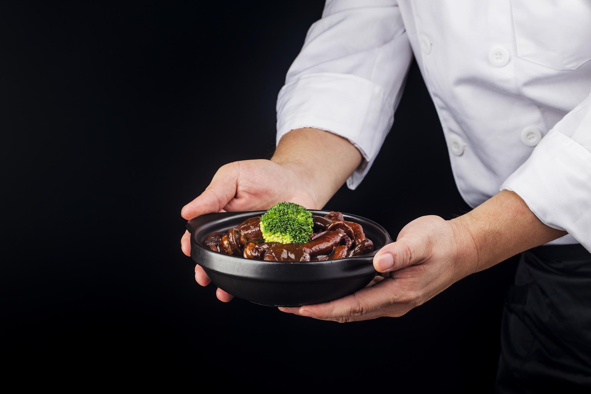 Chef plating a modern dish under studio lights