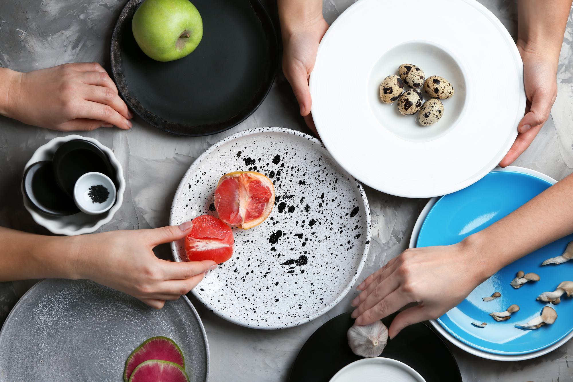 Three hands arranging tasting plates on a counter